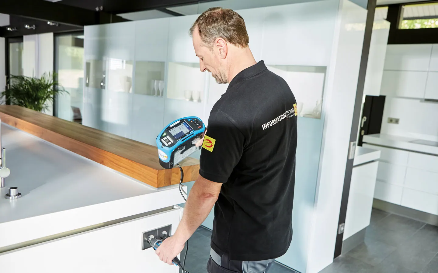 E-CHECK - Mitarbeiter prüft die Steckdosen in der Küche · B+B Mess- und Sicherheitstechnik