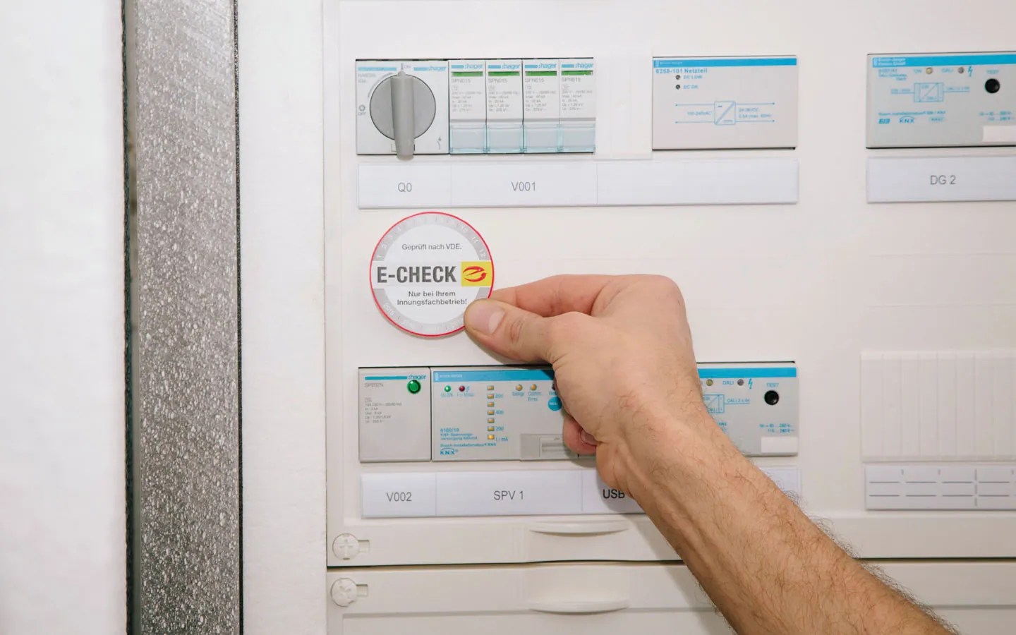 E-CHECK - Mitarbeiter klebt in der Verteilung die E-CHECK Plakette an · B+B Mess- und Sicherheitstechnik